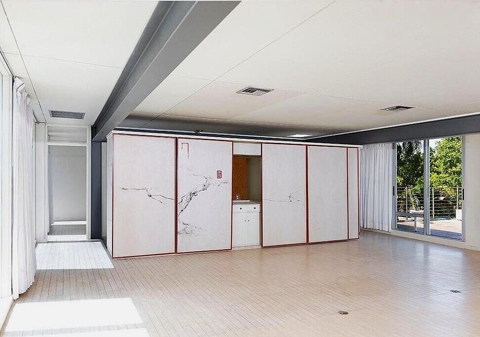 LEFT:  An interior view of the Biggs Residence in 1959—showing the house in its original state, as designed by Paul Rudolph.  This view of the central living-dining area is towards the dining table at the end of the room, which sits near the storage…